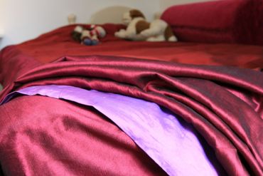 Rosa, rødt, og lilla sengetøy i silke