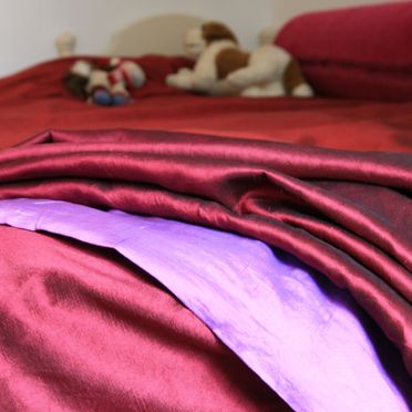 Rosa, rødt, og lilla sengetøy i silke